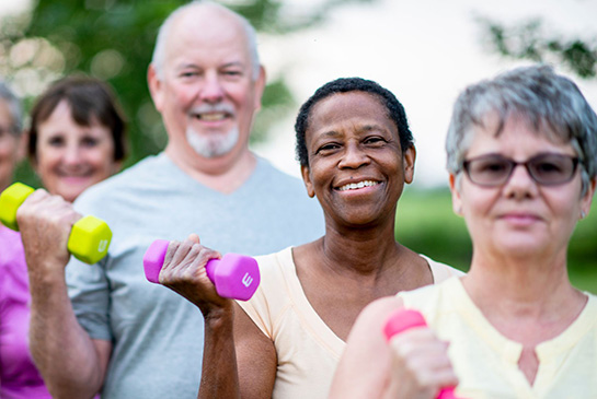 People smiling and holding dumbbells. 